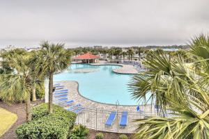 an overhead view of a pool with blue chairs and palm trees at Barefoot Resort Condo with Balcony and Pool Views! in Myrtle Beach