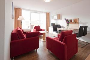 a living room with red chairs and a table at Exquisit 7 in Norderney
