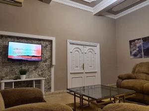 uma sala de estar com uma mesa e uma televisão na parede em Especially villa with private entrance, garden and parking no Cairo