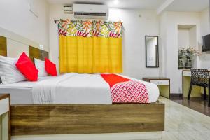 1 dormitorio con 1 cama con cortina amarilla y roja en OYO Nimalan Residency Shenoy Nagar Anna Nagar Near Pvr Cinemas Skywalk en Chennai
