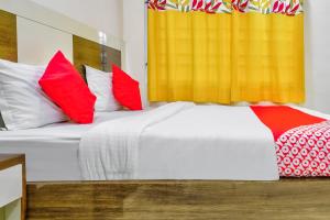 1 dormitorio con 2 camas y almohadas rojas y blancas en OYO Nimalan Residency Shenoy Nagar Anna Nagar Near Pvr Cinemas Skywalk en Chennai