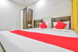 1 dormitorio con 1 cama blanca grande con almohadas rojas en OYO Nimalan Residency Shenoy Nagar Anna Nagar Near Pvr Cinemas Skywalk en Chennai