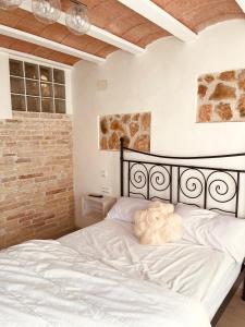 a white bed in a bedroom with a brick wall at El Nido: Una casita de ensueño in Deltebre