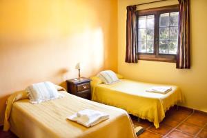 2 Betten in einem Zimmer mit gelben Wänden und einem Fenster in der Unterkunft Cortijo Puerta Casas Rurales in Órgiva + 36 Fotos