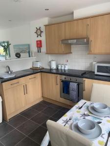 a kitchen with wooden cabinets and a table with plates on it at An Entire Fabulous Holiday Home - It’s All Yours! in Saint Columb Major