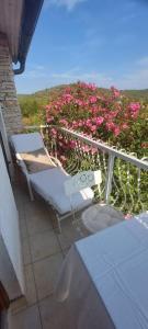 a balcony with two chairs and pink flowers at Studio apartman Tomi - seaview in Vis