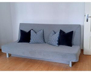 a gray couch with four pillows on it at Sea Side Apartment in Gdańsk