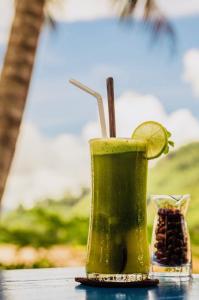 a green drink sitting on a table with a slice of lime at Villa Alounsavath Mekong Riverside in Luang Prabang