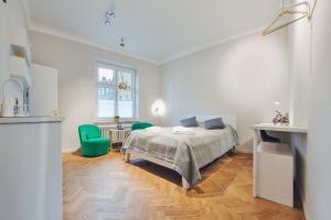 a white bedroom with a bed and a green chair at Apartamenty Sun & Snow Old Town Gdańsk in Gdańsk
