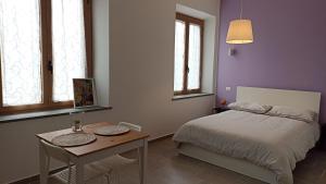 a bedroom with a bed and a table and windows at Il Glicine - monolocale in Paciano