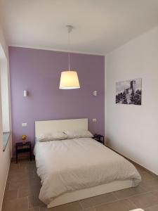 a bedroom with a bed with a purple wall at Il Glicine - monolocale in Paciano