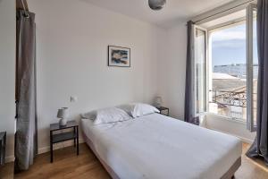 um quarto com uma cama branca e uma grande janela em Cosy Residence Paris Sud em Ivry-sur-Seine