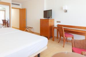um quarto de hotel com uma cama, uma secretária e uma televisão em Playamarina na Isla Canela