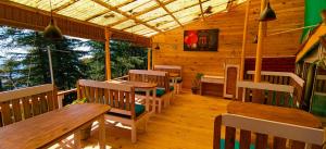 un restaurante con mesas de madera y sillas en un porche en Mcleodganj Bed & Breakfast, en McLeod Ganj