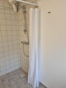 y baño con ducha con cortina blanca. en Feriehuse Hvide Sande, en Hvide Sande