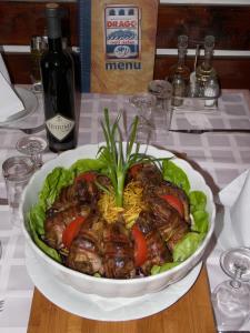 a white plate topped with meat and vegetables at Apartments and Rooms Drago in Sveti Stefan