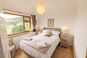 a bedroom with a large bed and a window at The Dormers - 5 BD Amazing Views of Stroud Valley 