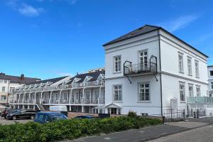ein weißes Gebäude mit auf einem Parkplatz geparkten Autos in der Unterkunft Nordstrandperle Ap H7 in Norderney