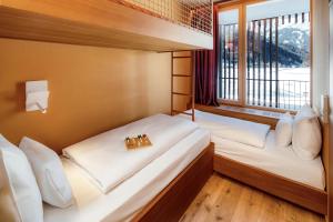 施伦斯Falkensteiner Family Hotel Montafon - The Leading Hotels of the World的一间带窗户的小房间里有两张床