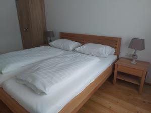 a bed with two white pillows and a night stand at Ferienwohnung Salzafeld in Bad Mitterndorf