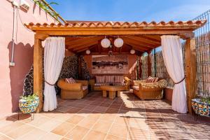 een patio met een houten pergola en stoelen bij Villa Paulito El Roque in Agüimes