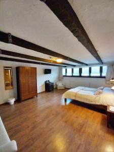 een grote slaapkamer met een bed en een houten vloer bij Sári Csárda Panzió in Dunakiliti