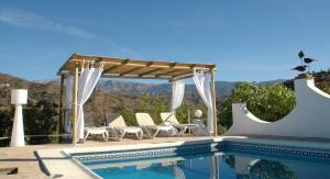 a pool with a gazebo and chairs next to a pool at Casa la Flor, villa with seaview in region Malaga in Sayalonga