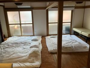 2 camas en una habitación con 2 ventanas en Casa Viento Stay Inn, en Hiroshima