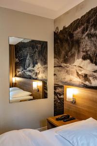 シャフハウゼンにあるホテル クローネンホフのベッド2台が備わる客室で、壁には絵画が飾られています。