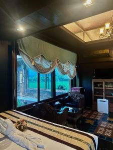 a bedroom with a bed and a large window at Bantunglom Resort in Mae Rim