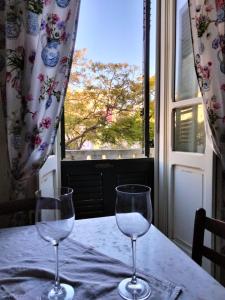 due bicchieri da vino seduti su un tavolo di fronte a una finestra di Casa jacaranda a Cagliari