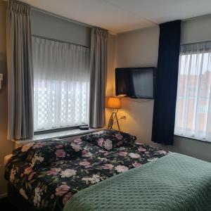 a bedroom with a bed and a tv and windows at B&B LandLust Guesthouse "Stay In Style " Amsterdam Area in Purmerend