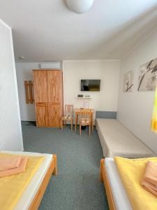 Habitación pequeña con 2 camas y mesa. en Slunečný Penzion, en Tasovice