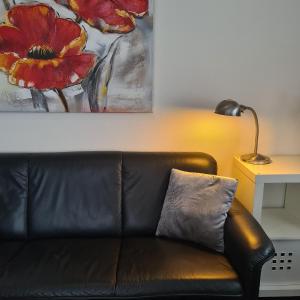 a black leather couch in a living room with a painting at LandLust Guesthouse B&B "Stay In Style " Amsterdam Area in Purmerend