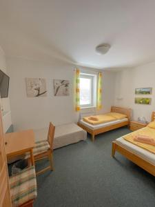 a room with two beds and a table and chairs at Slunečný Penzion in Tasovice