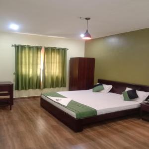 a bedroom with a large bed and a green window at Olive Residency 4BHK Villa with a Parking, Wifi, Campfire, Homemade Food in Kodaikānāl