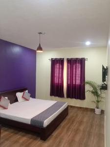 a bedroom with a bed and a purple wall at Olive Residency 4BHK Villa with a Parking, Wifi, Campfire, Homemade Food in Kodaikānāl