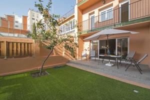 eine Terrasse mit einem Tisch mit einem Sonnenschirm und einer Liegewiese in der Unterkunft Holiday home Splendid Park Güell in Barcelona