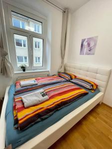 a bed with a colorful blanket and a window at Deluxe Studio 3P TH in Vienna