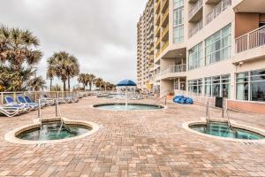 a patio with two pools and chairs and a building at Oceanfront Resort Condo in North Myrtle Beach in Myrtle Beach