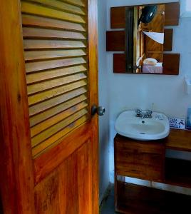 baño con puerta de madera y lavamanos en Kamala Surf & Backpacker Hostel, en Montañita