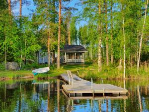 una casa en el agua con un muelle y un barco en Lomamokkila Cottages, en Savonlinna