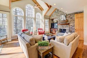 a living room with couches and a stone fireplace at Lake Access and On-Site Creek Lake Toxaway Home! in Lake Toxaway