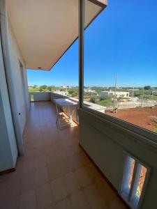 einen Balkon mit einem Tisch und einem großen Fenster in der Unterkunft Casa Linda in Cisternino