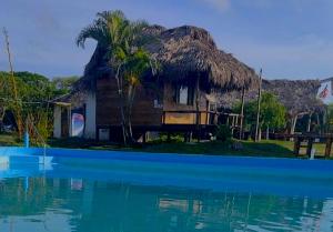a house with a straw roof next to a body of water at Kamala Surf & Backpacker Hostel in Montañita