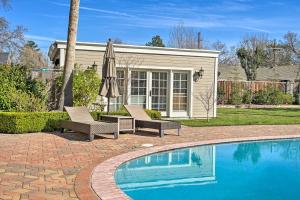 a patio with two chairs and an umbrella next to a pool at Pleasant Hill Studio with Pool and Hot Tub Access in Pleasant Hill