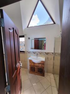 Villa with 6 bedroom en-suite في ريفير نوار: حمام مع حوض ونافذة كبيرة