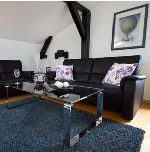 a living room with a black couch and a glass table at Hein-Sonnenschein in Wulfen auf Fehmarn