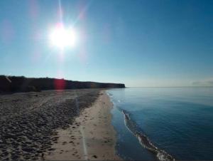 a view of a beach with the sun in the sky at Hein-Sonnenschein in Wulfen auf Fehmarn