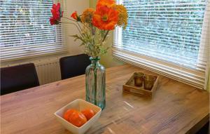 a vase with flowers and a bowl of oranges on a table at Stunning Home In Vorden With Wifi in Vorden